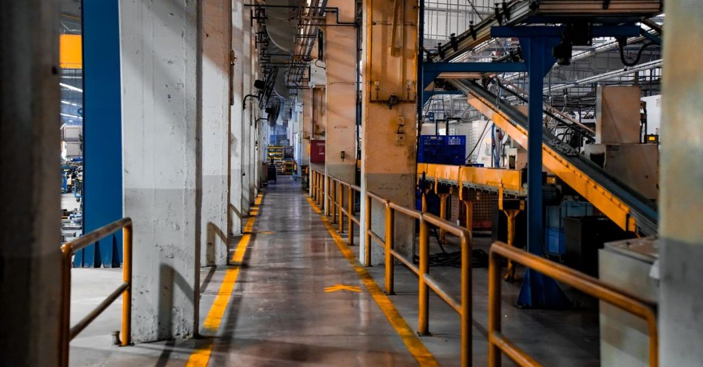 Inside view of an industrial factory featuring conveyor belts and empty walkways.