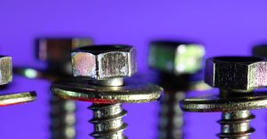 Detailed macro shot of metallic screws and bolts against a striking purple backdrop.
