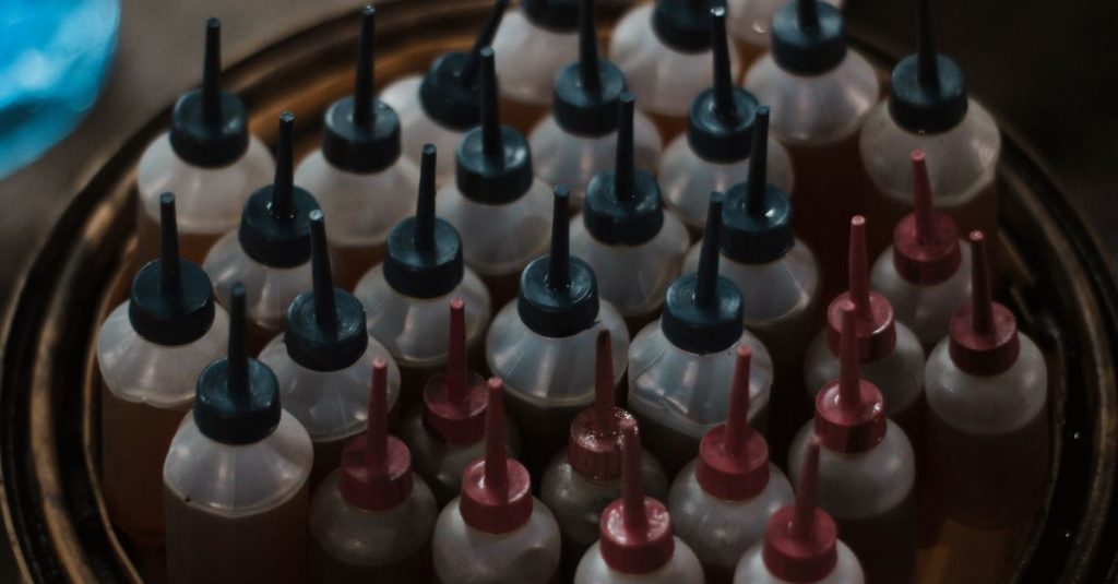 Assorted small squeeze bottles with colorful caps viewed from above in dim lighting.
