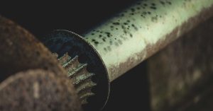 Closeup of old weathered rusty pipe of metal mechanism in industrial workshop against blurred background