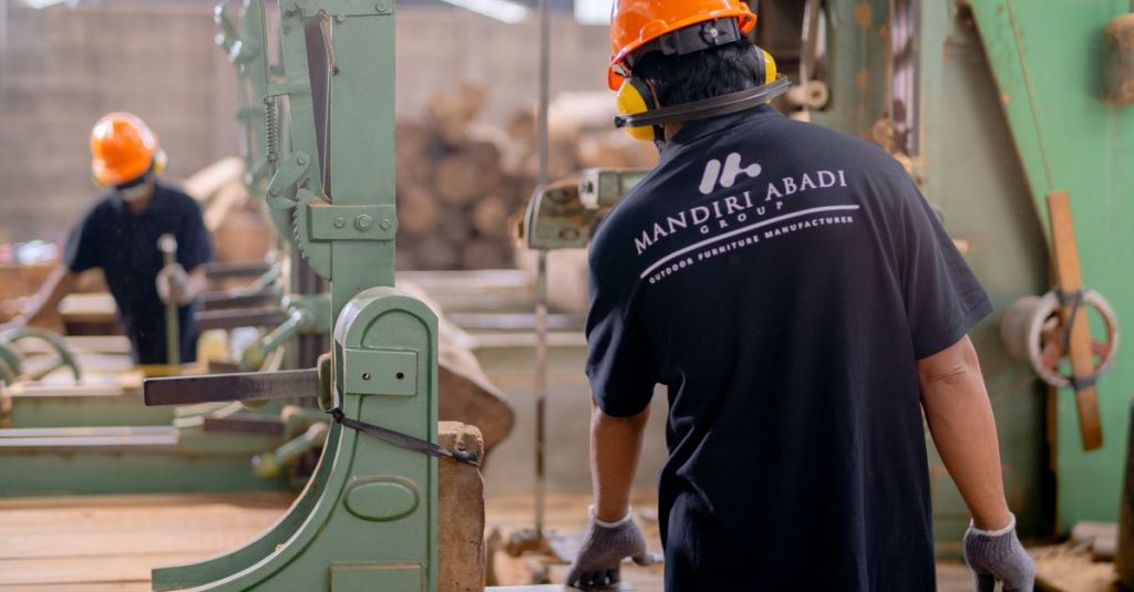 Workers wearing protective gear operating machinery in a factory environment, focusing on safety and production.