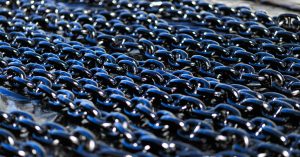 Detailed view of shiny industrial metal chains arranged outdoors, showcasing texture and metallic quality.