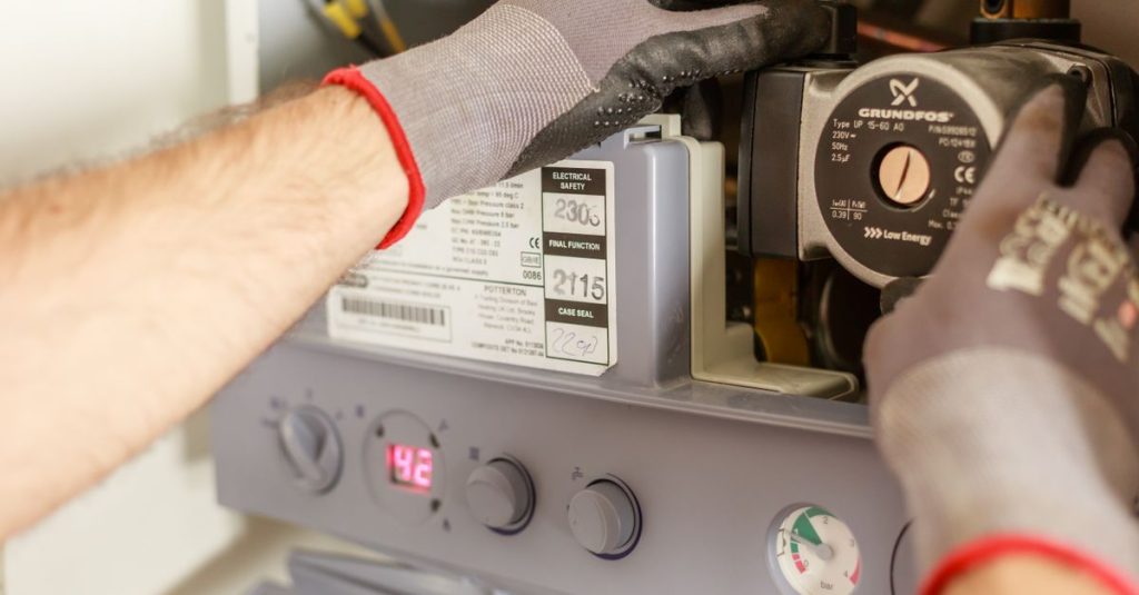 Close-up of hands adjusting a boiler system with precise instrumentation, showing maintenance work.