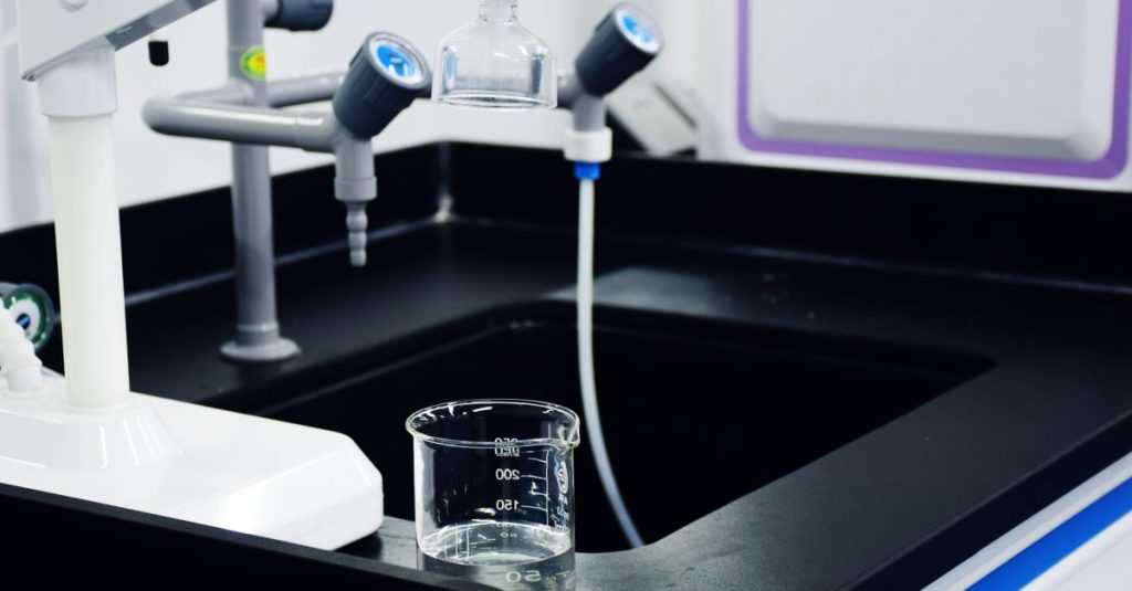 Close-up of laboratory equipment used for water filtration, featuring beakers and faucets.