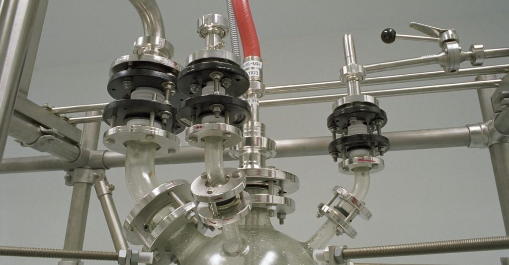 Close-up of stainless steel pipes and valves in a chemical industry setting.