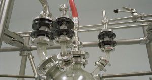 Close-up of stainless steel pipes and valves in a chemical industry setting.