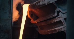Molten metal pouring from ladle in industrial foundry, capturing the intense heat and energy.