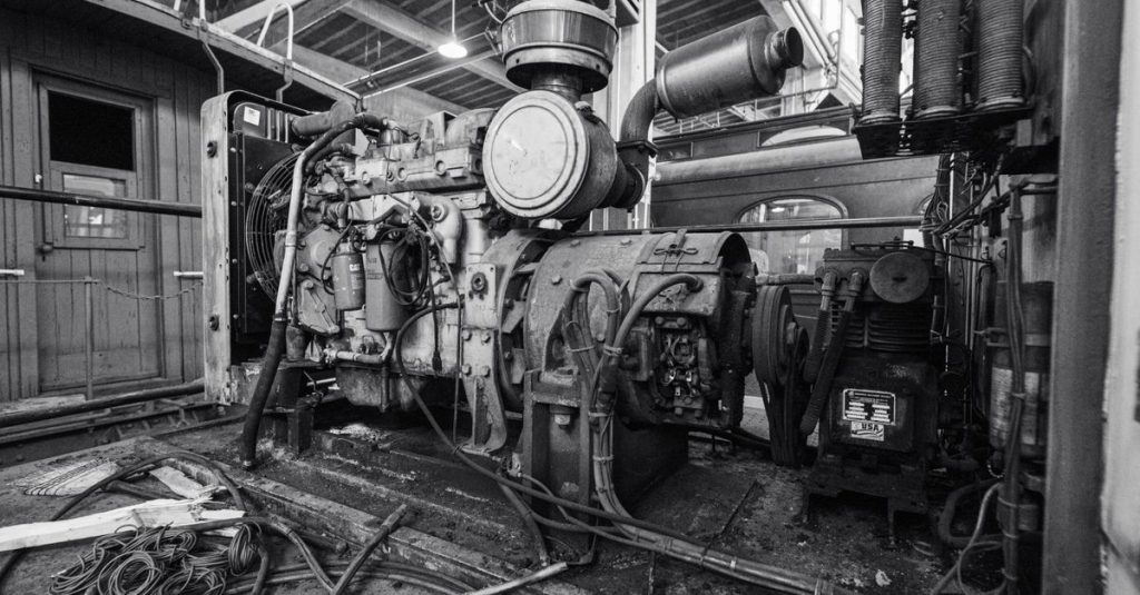 Black and white image of a vintage industrial engine inside a building.