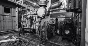 Black and white image of a vintage industrial engine inside a building.