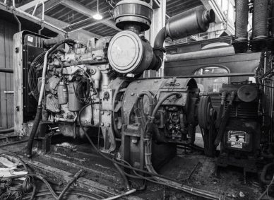 Black and white image of a vintage industrial engine inside a building.