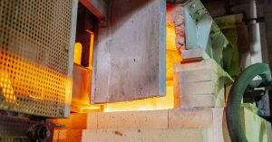Close-up view of a working glass furnace in an industrial setting, showcasing high-temperature operations.