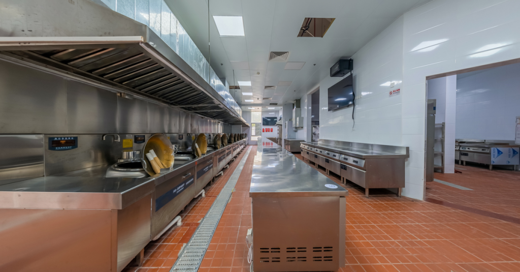 Modern industrial kitchen interior featuring stainless steel appliances and tiled flooring, ideal for commercial use.