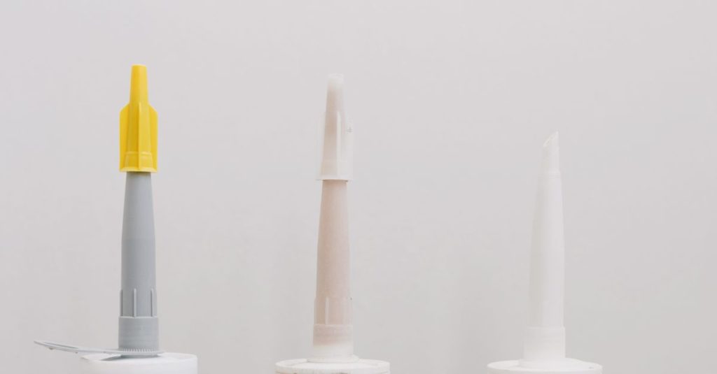 Set of various plastic tubes with glue for renovation works in workshop against white background