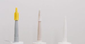 Set of various plastic tubes with glue for renovation works in workshop against white background