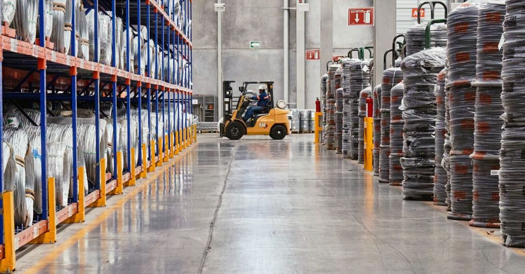 A forklift operates in an industrial warehouse with stacked goods. Efficient distribution setting.